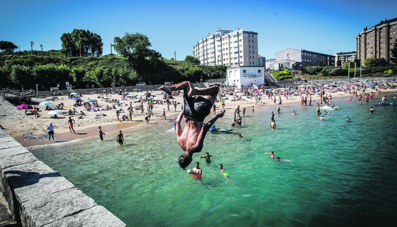 Un joven se arroja al agua en la playa de San Amaro en plena ola de calor