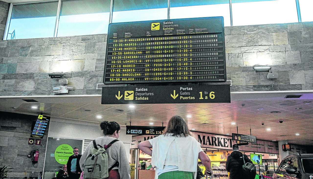 Viajeras junto al tablero de destinos del aeropuerto de Alvedro Paneles del aeropuerto de Alvedro