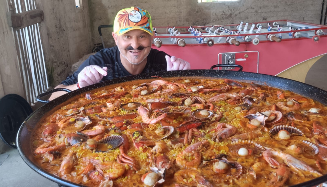 El cocinero posa con una de sus paellas
