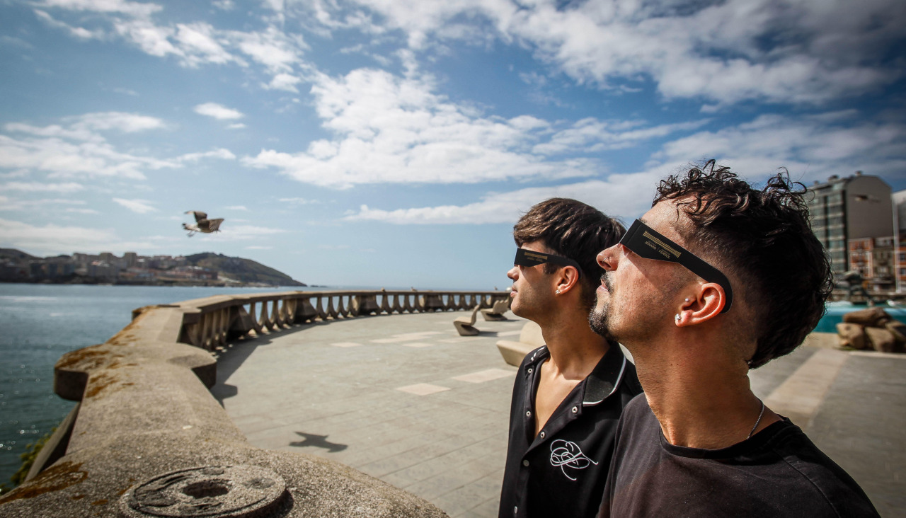 Dos personas observan el sol desde el Paseo Marítimo con gafas para el eclipse