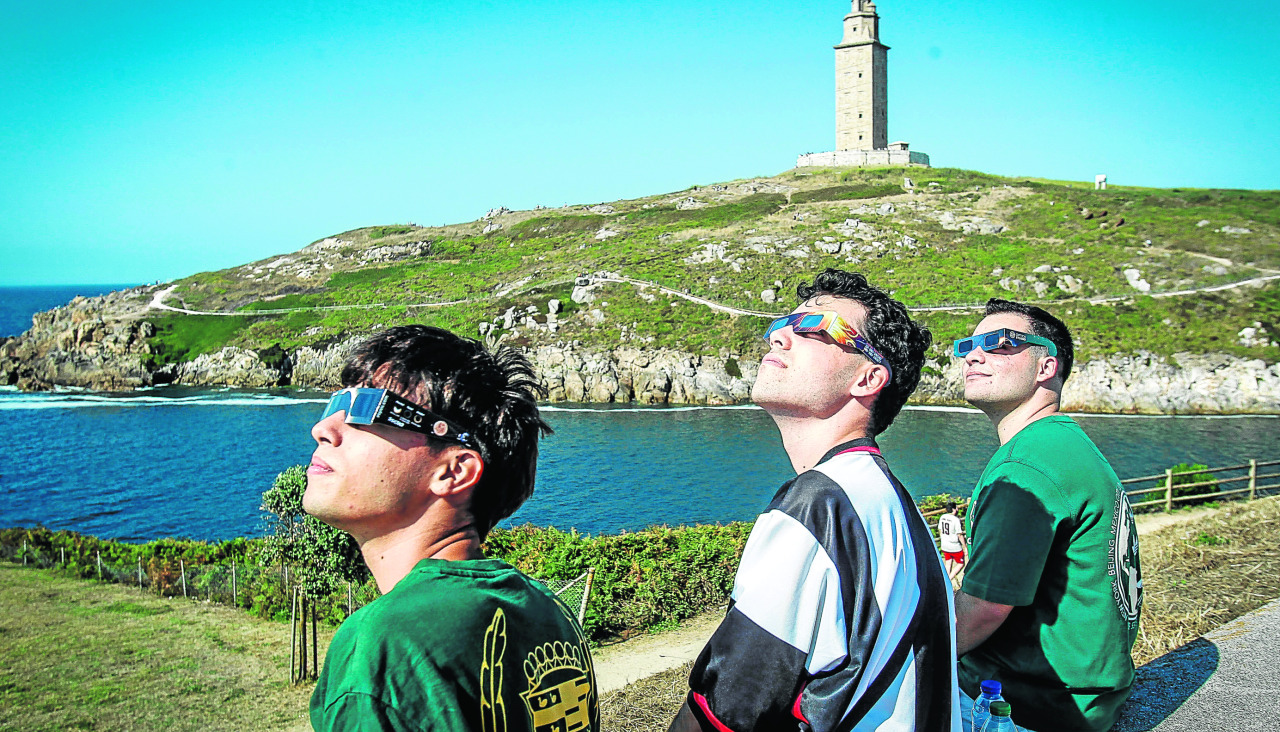 Tres personas, preparadas para el eclipse, cerca de la Torre de Hércules