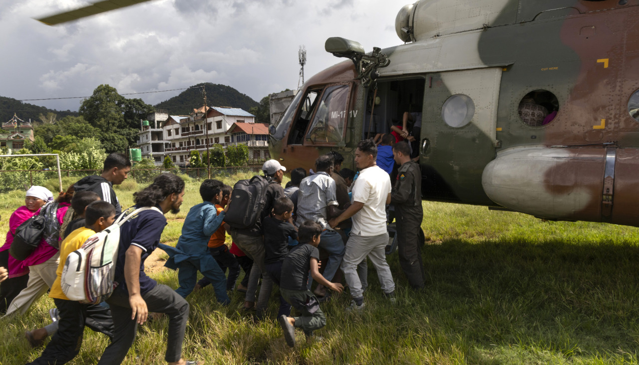 Un grupo de gente corre hacia un helicóptero del Ejército de Nepal durante una operación de rescate tras las inundaciones repentinas, en el pueblo de Hatigauda