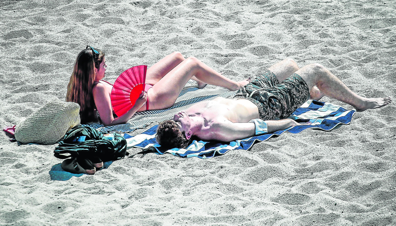 Dos personas toman el sol, en la playa de Riazor Día de sol y calor en a CoruñaA Coruña se abona a los 30 grados y ya van cinco jornadas en un mes en las que se supera esta barreraPasadas las 14.20 horas la estación del Observatorio llegó a los 33,9, el segundo valor más alto de este 2026