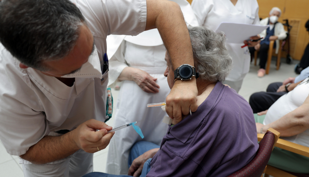 Un sanitario vacuna contra la gripe a una persona mayor