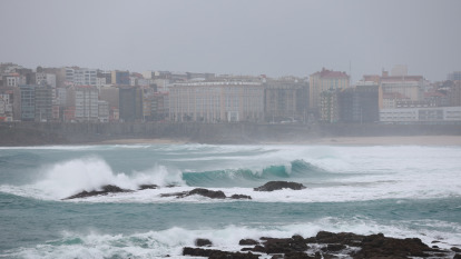 Surfistas en la playa en medio de una alerta naranja